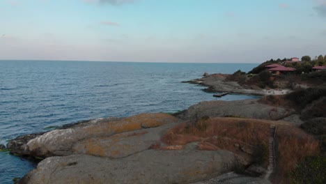 Aerial-shot-over-the-rocky-seashore,-filmed-by-drone-before-sunset,-clip-end-in-open-sea---Lozenets,-Bulgaria