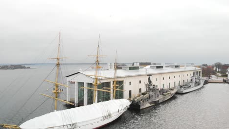 Decending-aerial-footage-of-the-ship-HMS-Jarramas-and-two-military-ships-docked-to-a-musem
