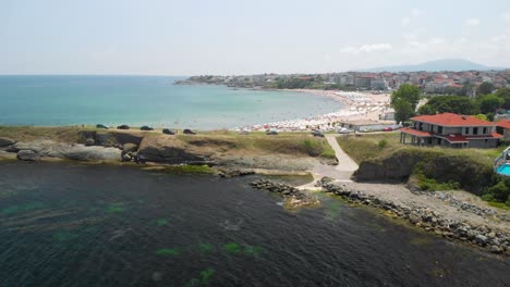 Fast-drone-flight-over-rocky-seashore-and-buildings-in-sunny-summer-day