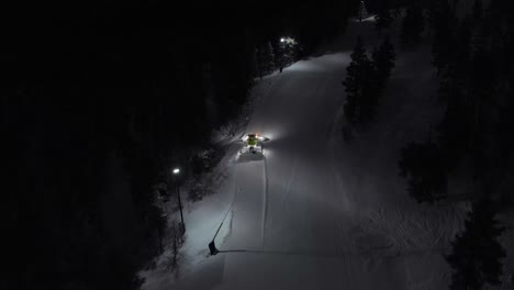 Aerial-of-snow-machine-at-work-in-Idre,-Sweden-during-a-late-evening-in-the-dark-4