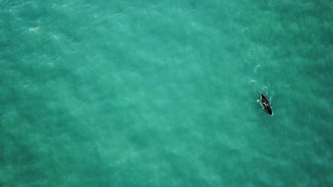 Aerial-footage-pointed-down-at-deep-blue-water-and-kayaker
