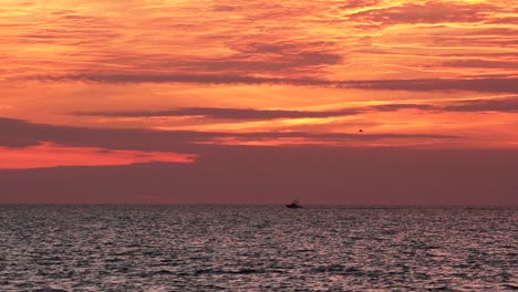 Twilight-on-the-ocean-with-a-luxury-Fishing-boat-and-bird-flying-in-the-distance