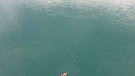 Drone-footage-of-longtail-boat-navigating-around-islands-of-Krabi,-Thailand-with-the-limestone-rock-formations-sticking-out-of-the-water-and-the-ocean-in-background-1