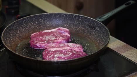 Raw-steaks-going-into-a-frying-pan