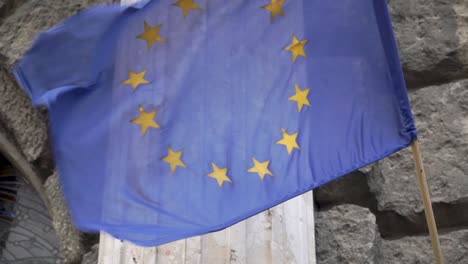 Waving-flag-of-European-union-in-front-of-stone-wall-1