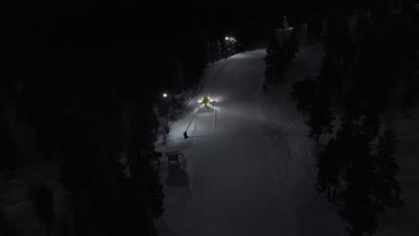 Aerial-of-snow-machine-at-work-in-Idre,-Sweden-during-a-late-evening-in-the-dark-5