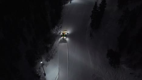 Aerial-of-snow-machine-at-work-in-Idre,-Sweden-during-a-late-evening-in-the-dark-3