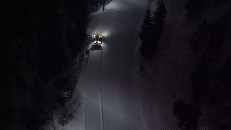 Aerial-of-snow-machine-at-work-in-Idre,-Sweden-during-a-late-evening-in-the-dark-2