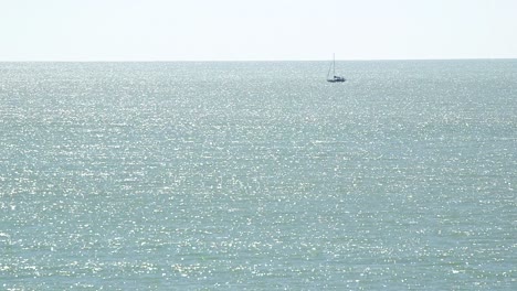 Wide-shot-of-Monochromatic-sea-with-small-sailboat-in-the-distance