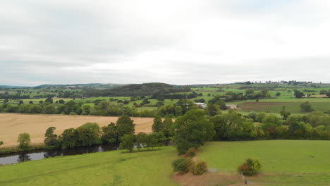 Drone-Flying-Above-Green-Fields-and-River-with-Hills-on-the-Horizon-Cinematic-Drone-Footage-in-Yorkshire