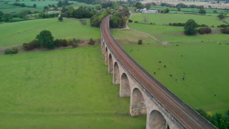 Drohne-über-Modernem-Zug-Auf-Viadukt-Mit-Filmischer-Landschaft-Drumherum