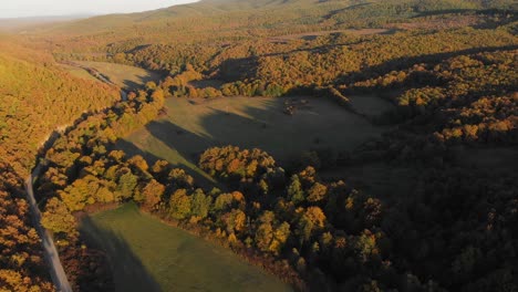 Aerial-drone-shot-of-grass-fields-and-forests-at-sunset