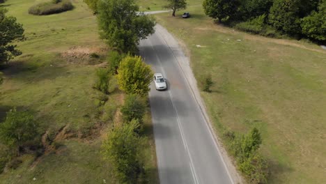 Aerial-drone-shot-over-extra-urban-road-and-car-drive-uphill-2