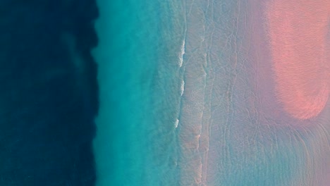 Farbenfroher-Blick-Von-Oben-Nach-Unten-Von-Einer-Drohne-über-Tosende-Meereswellen-Mit-Verschiedenen-Blau--Und-Türkistönen-Und-Minimalem-Sand