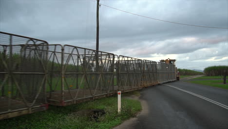 Empty-yellow-sugar-cane-train-driving-over-road-crossing