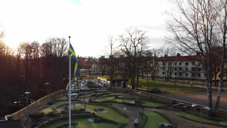 Footage-of-a-small-Swedish-flag-blowing-in-the-wind-on-a-miniature-golf-course-in-Orgryte,-Gothenburg,-Sweden