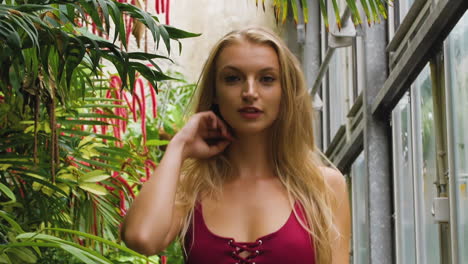 Close-up-of-a-Caucasian-blonde,-swimwear-model,-walking-and-smiling-in-a-botanic-garden