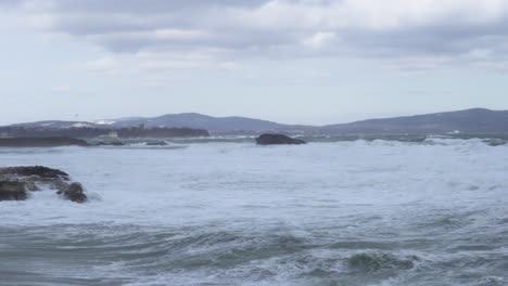 Panning-shot-of-winter-rocky-sea-coast-in-high-wind-and-big-waves