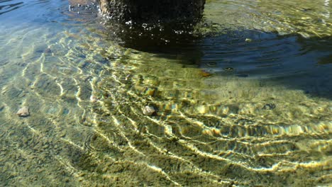 Nice-detail-of-the-reflections-and-waves-of-water-from-a-stone-fountain-with-water-splashing
