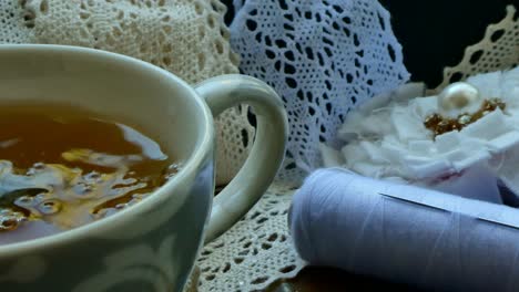 Pouring-water-in-a-cup-of-tea-in-a-tray-with-materials-for-sewing