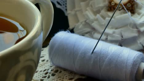 Close-up-of-a-yarn-package-and-a-needle-in-a-tray-with-a-cup-of-tea