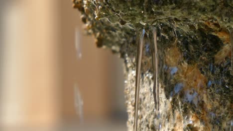 Close-up-detail-of-one-side-of-an-ancient-stone-fountain-and-water-falling-1