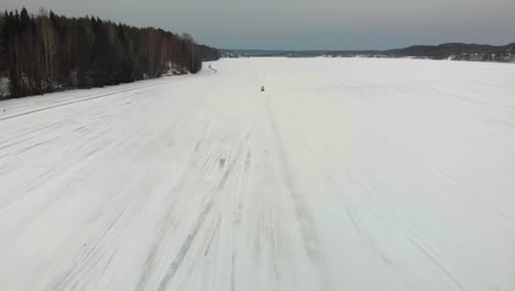 Aerial-shot-of-a-man-driving-his-snowmobile-towards-the-camera-on-Indalsalven-in-Timra,-Sundsvall,-Sweden