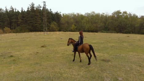 Low-aerial-tracking-shot-of-girl-ride-horse-in-grass-field-1