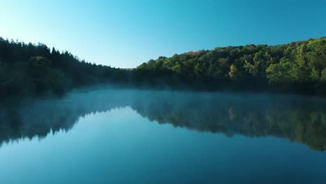 Early-morning-low-drone-shot-over-glossy-lake-with-some-fog-1