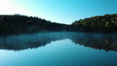 Early-morning-low-drone-shot-over-glossy-lake-with-some-fog-4