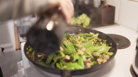 Woman-cooking-wok-with-mushrooms,-brocolli,-chili,-noodles,-leek,-suger-peas-and-soy-1