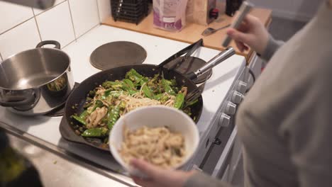 Woman-cooking-wok-with-mushrooms,-brocolli,-chili,-noodles,-leek,-suger-peas-and-soy