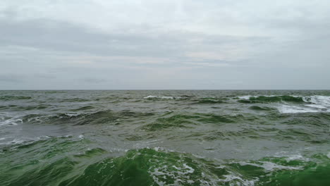 Dark-green-and-wild-sea-waves-captured-by-a-drone-on-a-cloudy,-windy-day