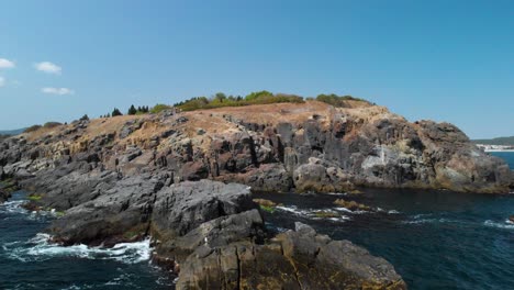 Aerial-pan-shot-around-big-rocks-in-the-sea-next-to-the-shore-in-sunny-summer-day-3