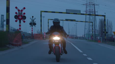 Stunning-footage-of-a-motorcyclist-fully-dressed-in-black,-riding-with-a-sporty-red-motorcycle-in-an-industrial-zone-at-night