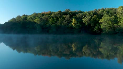 Early-morning-panning-shot-over-glossy-lake-with-some-fog
