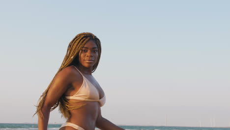 African-swimwear-model-with-braids-having-fun-posing-at-the-beach-during-a-sunset
