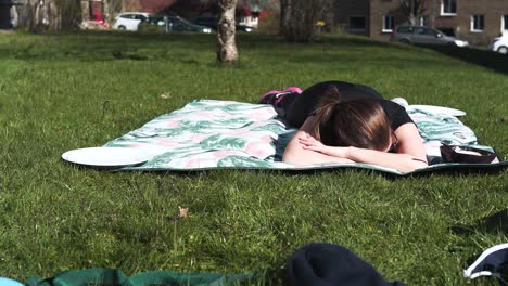 Woman-laying-on-a-blanket-in-the-sun-after-a-hard-workout,-totally-exhausted-1