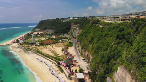 Drone-flying-above-the-road-leading-to-the-Pandawa-Beach-in-Bali,-Indonesia