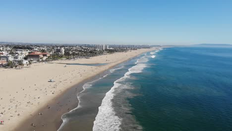 Drone-footage-taken-from-400-feet-of-the-pristine-Santa-Monica-beach-in-Los-Angeles,-with-waves-rolling-across-the-soft-white-sand