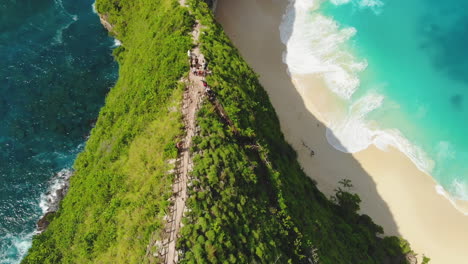 Slow-motion-aerial-of-tourists-hiking-on-steep-forested-cliffs-of-Nusa-Penida