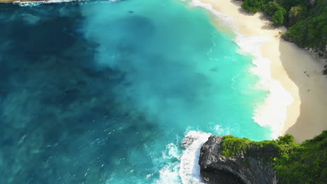 Amazing-scenery-of-clear-blue-waters-and-bright-white-waves-hitting-a-tropical-beach,-slow-motion-footage