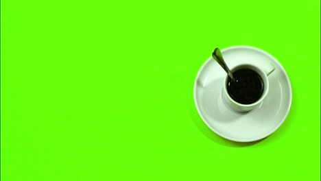 Stoppen-Sie-Die-Bewegung-Auf-Einem-Grünen-Hintergrund-Der-Kaffeeuhr,-Wo-Sich-Der-Löffel-Einer-Kaffeetasse-Dreht-Und-Am-Ende-Der-Kaffee-Verschwindet