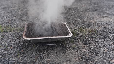 Pouring-water-on-a-disposable-barbecue-to-put-out-the-glow-from-the-coal-and-extinguish-the-grill