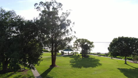 Drone-Dolly-Down-from-Setting-Florida-Sun-through-Trees-into-Lakeside-Park-Lake-Apopka