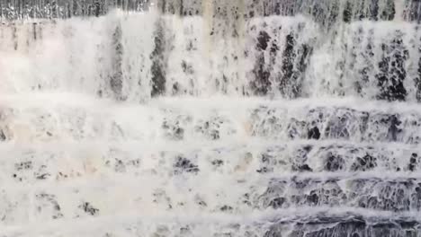 Wasser,-Das-Einen-Steinernen-Wasserfall-Hinunterläuft,-Umgeben-Von-Bäumen-Und-Viel-Grün-3