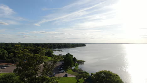 Flying-over-a-beautiful-lakeside-park-as-the-Florida-Sun-begins-to-set-through-the-trees