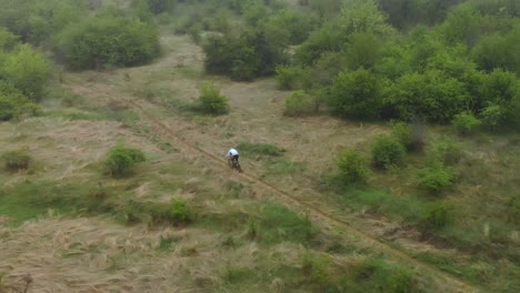 Aerial-tracking-shot-of-fast-moutain-bike-rider-in-small-path