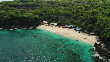 Descending-drone-flying-inland-to-the-amazing-secret-white-sand-beach,-Bias-Tugel-Beach-in-Bali