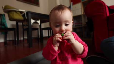 Cute-little-baby-eats-a-wood-toy-in-front-of-the-camera,-shot-in-slow-motion